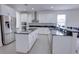 Modern white kitchen featuring stainless steel appliances, an island, and granite countertops at 5201 Villa Rosa Ave, St Cloud, FL 34771