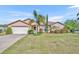 Charming single Gathering home with a two-car garage and beautiful landscaping with green grass and palm trees at 789 Kangaroo Ct, Deltona, FL 32738