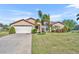 Charming single Gathering home with a two-car garage and beautiful landscaping with green grass and palm trees at 789 Kangaroo Ct, Deltona, FL 32738