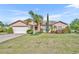 Charming single Gathering home with a two-car garage and beautiful landscaping with green grass and palm trees at 789 Kangaroo Ct, Deltona, FL 32738