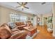 Spacious living room with hardwood floors, a comfortable leather sofa, and abundant natural light from the window at 789 Kangaroo Ct, Deltona, FL 32738