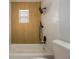 Bathroom featuring wood-look shower tile, a white tub, toilet and tile, and black fixtures at 10526 Fernando St, Orlando, FL 32825