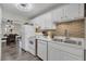 Bright kitchen with white cabinetry, stainless sink, tile backsplash, and a view into the adjacent dining area at 134 Roberta Rd, Ormond Beach, FL 32176