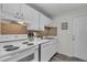 Bright kitchen with white cabinetry, stainless sink, tile backsplash, and a door to the exterior at 134 Roberta Rd, Ormond Beach, FL 32176