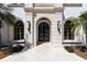 Grand entrance featuring a stone archway, dark wood double doors, and symmetrically placed plants at 14645 Isleview Dr, Winter Garden, FL 34787