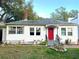 Charming single-story home featuring a vibrant red front door, manicured garden beds, and classic white siding at 1919 Waldo St, Orlando, FL 32806