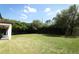 Spacious backyard featuring lush green grass, mature trees, and a view of the covered patio at 2351 Kelbrook Ct, Oviedo, FL 32765