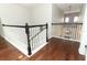 Upstairs hallway featuring hardwood style floors, dark wood railing, and white painted railings at 2351 Kelbrook Ct, Oviedo, FL 32765