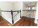 Upstairs hallway with hardwood flooring and white railing with black accents, offering a bright and airy space at 2351 Kelbrook Ct, Oviedo, FL 32765