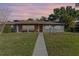 Charming single-story home with a well-manicured lawn, walkway, and colorful sunset backdrop at 2805 Bongart Rd, Winter Park, FL 32792