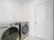 Well-lit laundry room featuring modern appliances, clean white walls and an entrance door at 2820 Black Birch Dr, Ocoee, FL 34761
