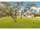 Lush front yard with mature trees framing a well-maintained home with a blue front door at 30041 Redoak Ave, Eustis, FL 32736
