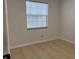 A simple bedroom featuring light-colored walls, tiled floors and a sunlit window with blinds at 3106 Garden Ct, St Cloud, FL 34769