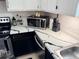 Well-lit kitchen boasts white cabinets and black and white marbled countertops with stainless steel appliances at 3106 Garden Ct, St Cloud, FL 34769