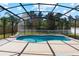 Inviting in-ground pool enclosed by a screen, set against a backdrop of mature trees and a charming picket fence at 3180 Town And Country Rd, Oviedo, FL 32766