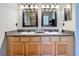 Bathroom with dual sinks, granite countertops, wood cabinets, and decorative mirrors and lighting at 712 Timberwilde Ave, Winter Springs, FL 32708