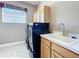 Bright laundry room with blue washer and dryer, a sink with cabinets, and window for natural light at 712 Timberwilde Ave, Winter Springs, FL 32708