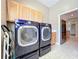 Laundry room with blue washer and dryer set, cabinets, and doorway to kitchen with stainless steel refrigerator at 712 Timberwilde Ave, Winter Springs, FL 32708