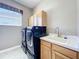 Well-lit laundry room with a window, front-loading machines, a sink, and storage cabinets at 712 Timberwilde Ave, Winter Springs, FL 32708