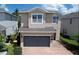 Two-story home with a two-car garage and brick driveway, complemented by lush landscaping at 7417 Marker Ave, Kissimmee, FL 34747