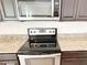 Stainless steel stove top oven is set in granite countertops with modern microwave above at 7417 Marker Ave, Kissimmee, FL 34747