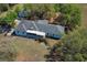 An aerial view of a charming light blue home with a grey roof, accented by verdant trees and a private backyard at 7435 Redwing Rd, Groveland, FL 34736