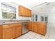 Kitchen featuring tile flooring, wood cabinets, stone countertops, and stainless steel dishwasher at 7435 Redwing Rd, Groveland, FL 34736