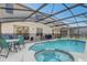 An inviting screened-in pool area with a spa, seating, and secure safety fence at 1028 Orange Cosmos Blvd, Davenport, FL 33837