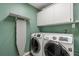 Laundry room featuring white cabinets, a folding ironing board, and modern washer/dryer at 111 Woodstream Ct, Maitland, FL 32751