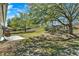Well-shaded backyard with large trees, a patio, an egg chair, and grill at 1137 Stratton Ave, Groveland, FL 34736
