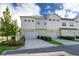 Exterior view of townhomes with two-car garages, manicured landscaping, and neutral paint at 13852 Maskawa Ave, Orlando, FL 32827