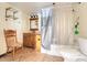 Traditional bathroom with a wood vanity, mirror, tub with shower and vintage chair at 15 E Mohawk Street, Mascotte, FL 34753