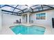 Covered pool with a chair and a table sitting on a white patio at 1563 Sandbagger Dr, Davenport, FL 33896