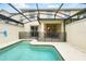 A private pool with a safety fence and a covered patio with an outdoor dining set behind the house at 1570 Sandbagger Dr, Davenport, FL 33896