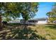 View of the spacious back yard with large shade trees, white fence and utility shed at 188 Citrus Dr, Kissimmee, FL 34743