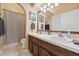 Well-lit bathroom featuring double sinks, wood cabinets, decorative mirrors, and a shower with a neutral curtain at 2321 E H Pounds Dr, Ocoee, FL 34761