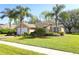 Charming single-story home with a well-manicured lawn, mature palm trees, and a brick-paved driveway at 2545 Azzurra Ln, Ocoee, FL 34761