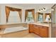 Bright primary bathroom features a soaking tub, vanity, and multiple windows with wood-style blinds at 2680 Lookout Ln, Kissimmee, FL 34746
