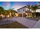 Beautiful home with a brick driveway, three-car garage, tropical palms, and warm exterior lighting at 2680 Lookout Ln, Kissimmee, FL 34746