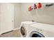 Well-equipped laundry area with modern washer, dryer, tiled floor, and functional shelving for storage at 2680 Lookout Ln, Kissimmee, FL 34746