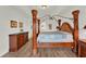 Spacious primary bedroom features a wooden four-poster bed, wood-look floors and tray ceilings at 2680 Lookout Ln, Kissimmee, FL 34746
