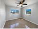 Bedroom features tiled floor, two windows, and a ceiling fan at 411 Thomas Ave, Frostproof, FL 33843