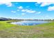 Scenic view of a tranquil community pond, reflecting the blue sky, surrounded by lush green lawns and neighborhood homes at 4180 Bull St, St Cloud, FL 34772