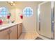 Bathroom featuring a double vanity, a decorative octagon window, and a glass-enclosed shower stall at 449 Martigues Drive, Kissimmee, FL 34759