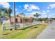 Single Gathering house on a sunny day with a white picket fence, palm trees and red driveway at 449 Martigues Drive, Kissimmee, FL 34759