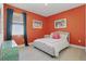 Comfortable bedroom with bright orange walls, natural light, and calming decor at 4778 Cragmere Loop, Clermont, FL 34711