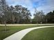Concrete walking path in a green space with mature trees under a blue sky at 4778 Cragmere Loop, Clermont, FL 34711