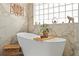Close-up of an elegant bathtub, decorated with potted plants, within a marble tiled bathroom at 5011 Dorian Ave, Belle Isle, FL 32812