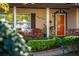 Charming front porch with a wooden chair, tidy landscaping, and a brightly painted orange front door at 5011 Dorian Ave, Belle Isle, FL 32812