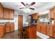 A kitchen with wood cabinets, stainless appliances, granite countertops, a ceiling fan, an island and two stools at 5011 Dorian Ave, Belle Isle, FL 32812